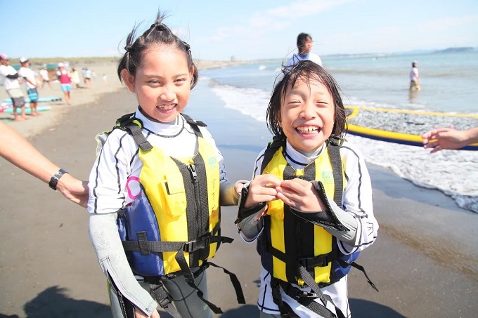 【写真】2人の女の子が、ボディスーツを着て砂浜で笑っている