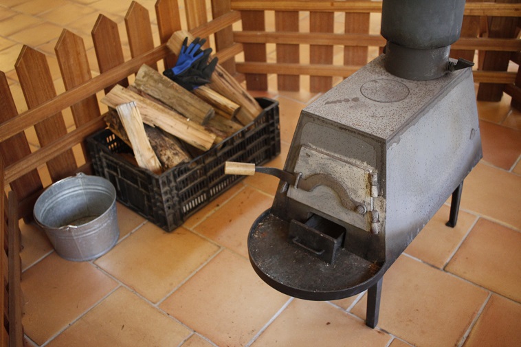 【写真】黒い薪ストーブの横には薪とバケツが置いてある