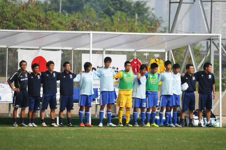 【写真】サッカーコートに向かって一列に並び、肩を組む選手たち。