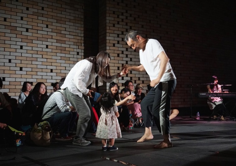 【写真】小さな女の子がダンスを踊る男性を見つめる。優しい雰囲気が流れている。