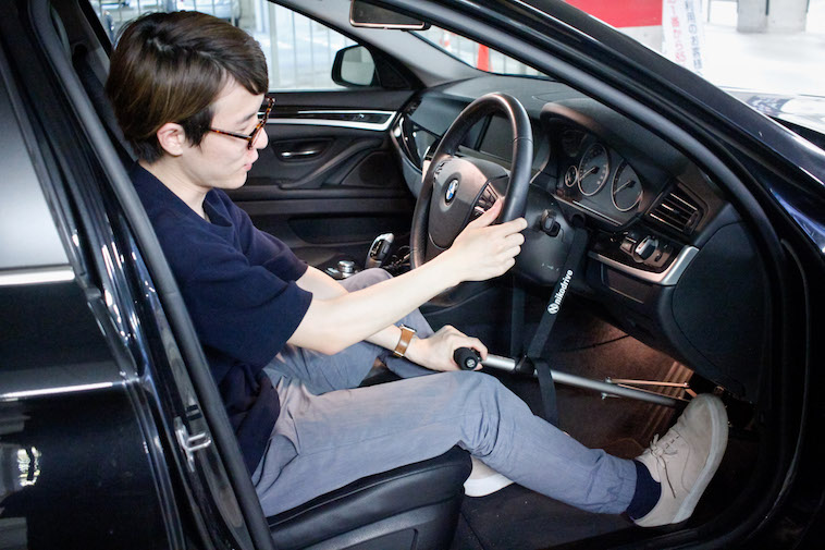 【写真】ハンドコントロールを使って車を運転しようとする男性