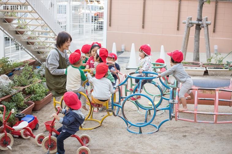 【写真】校庭の遊具で先生を囲んで遊ぶ子どもたち