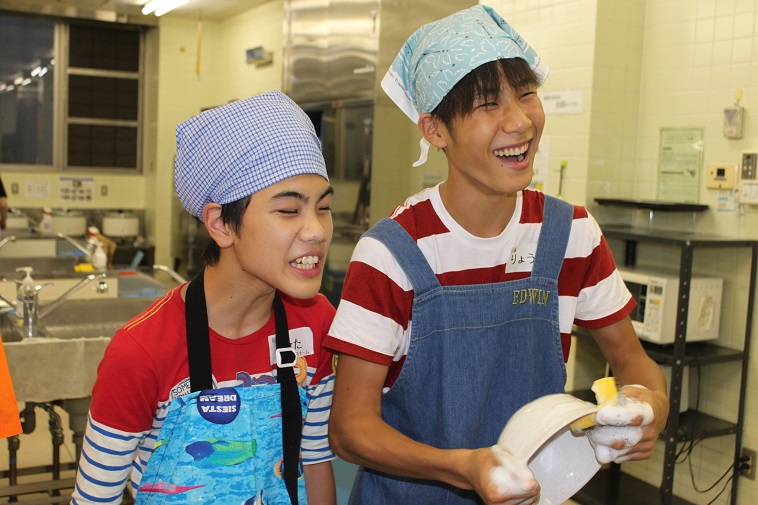 【写真】エプロンと三角巾をつけて、調理室で洗い物をする男の子