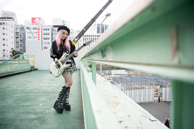 【写真】歩道橋の上でギターを持ちポーズをとるりささん