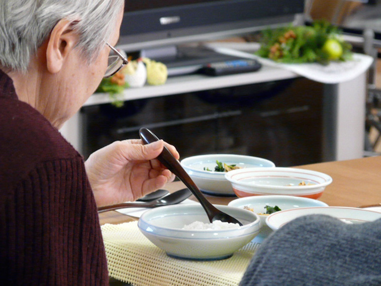 【写真】てまるのお皿とスプーンで食事をする高齢者