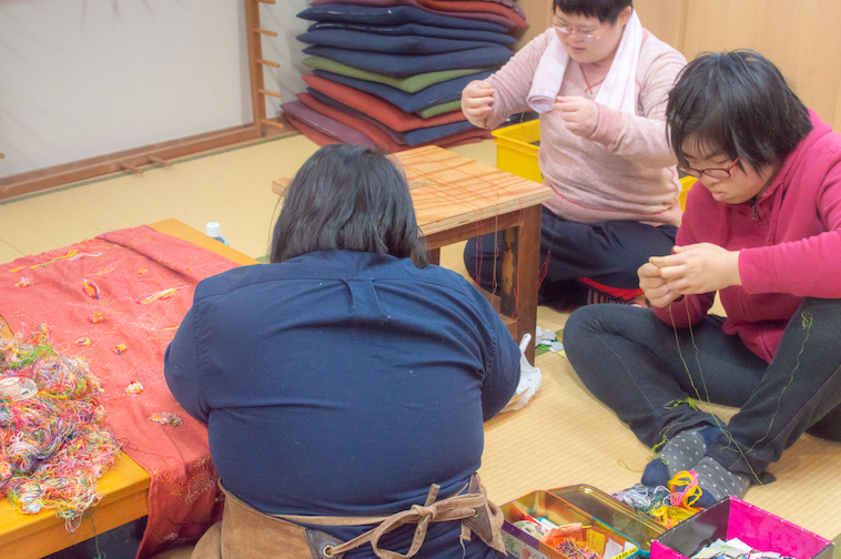 【写真】3人で集まって糸作りをするスタッフ