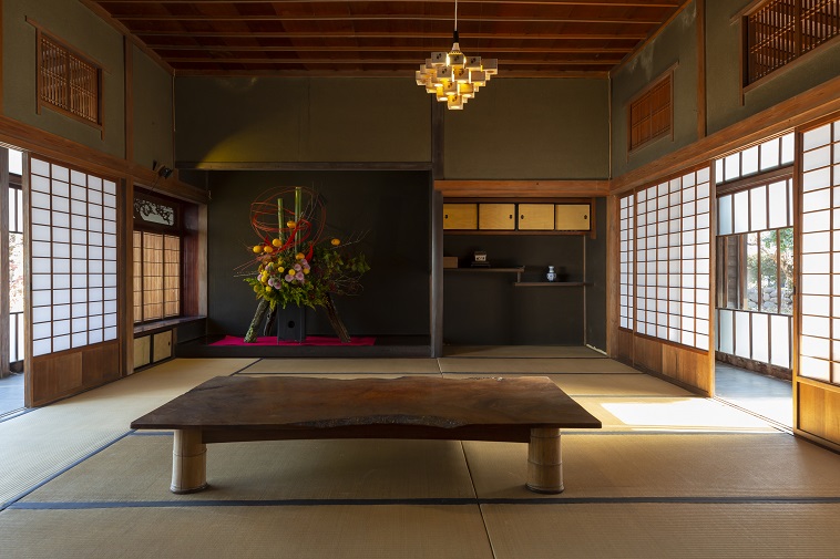【写真】古民家屋敷の内観。広い畳の部屋で、日本らしさを感じる落ち着いた空間。照明には日本酒を飲む枡が使われている。