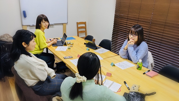 【写真】片耳難聴Cafeの様子。麻野さんと3人の参加者がテーブルを囲み、話している。