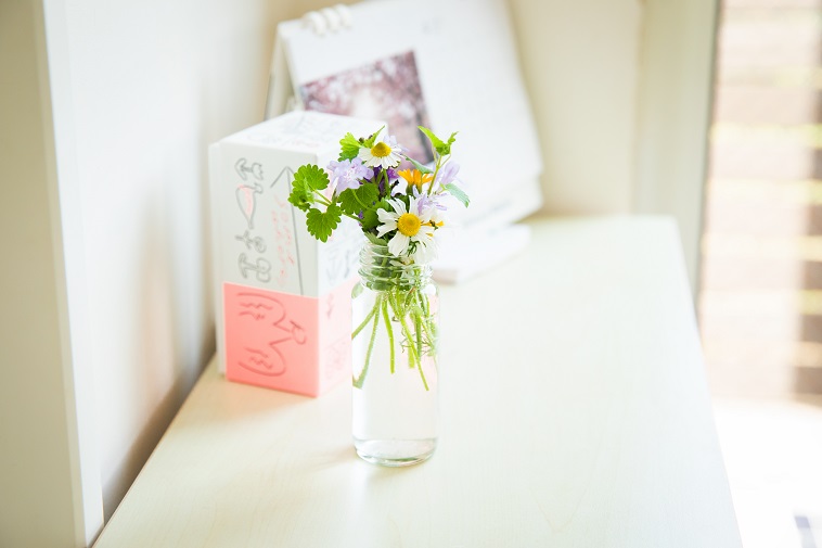 【写真】テーブルの上に飾られた花。小さな透明な瓶に、白や黄色の花が生けられている。