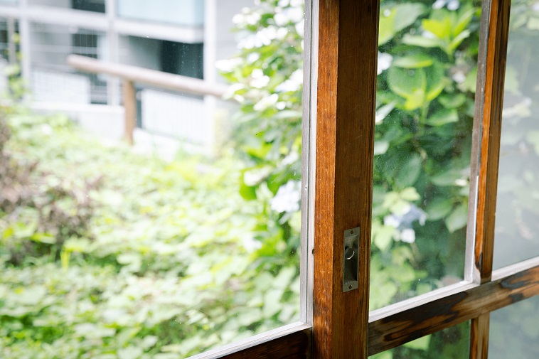 【写真】木の枠で作られた窓と、そこから見える景色。アジサイや緑がぼんやりと写っている。