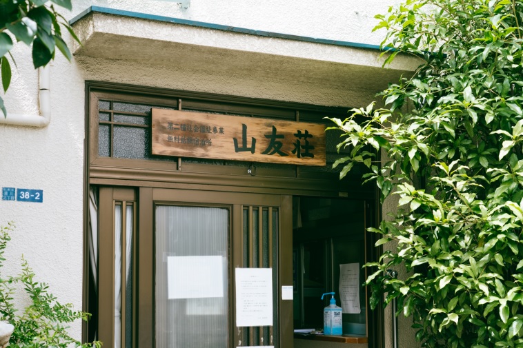 【写真】山友荘と書かれた木の看板がかかっている建物