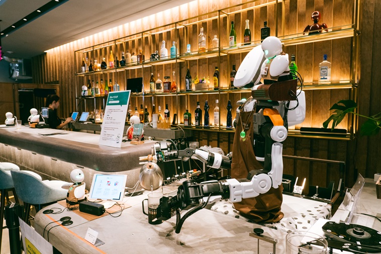 【写真】卓上のOriHimeの何倍もの大きさのロボット・テレバリスタ。右手にケトルを持ち、引いたコーヒー豆にお湯を注いでいる