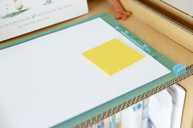 【写真】緑色のバインダーの上に置かれた白い紙と黄色のふせん