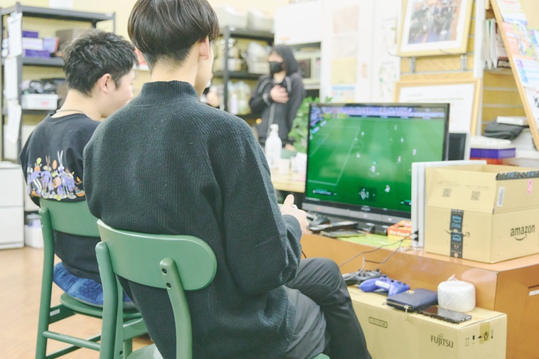 【写真】テレビゲームをしている若者2人の後ろ姿