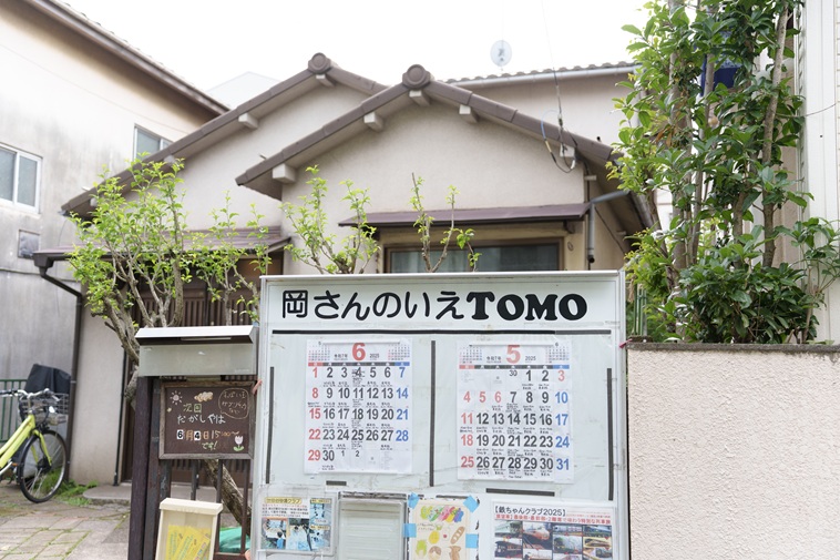 【写真】民家の前に岡さんのいえと書かれた大きな看板があり、カレンダーが貼られている