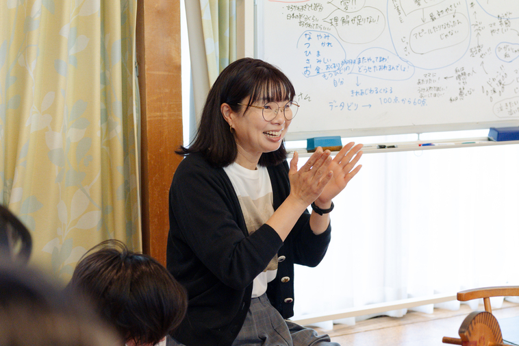 【写真】当事者研究の
ホワイトボードの前で笑顔で話をするえづれさん
