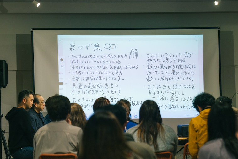  【写真】【写真】スクリーンに研究メモが映し出されている。「裏ワザ集」というタイトルと、その下には「たくさんの大人とふれ合ってもらう」「孤立した経験からもとをとる」「」一緒にとんでもないことをする」「まずは自分が幸せになる」などの言葉が書かれている。