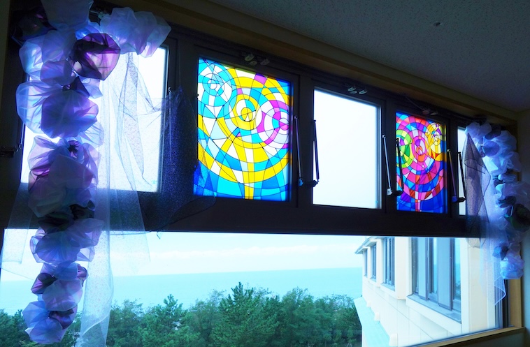 【写真】海に面した窓に施されたステンドグラス風の作品。透け感のある布でできた装飾もついている。