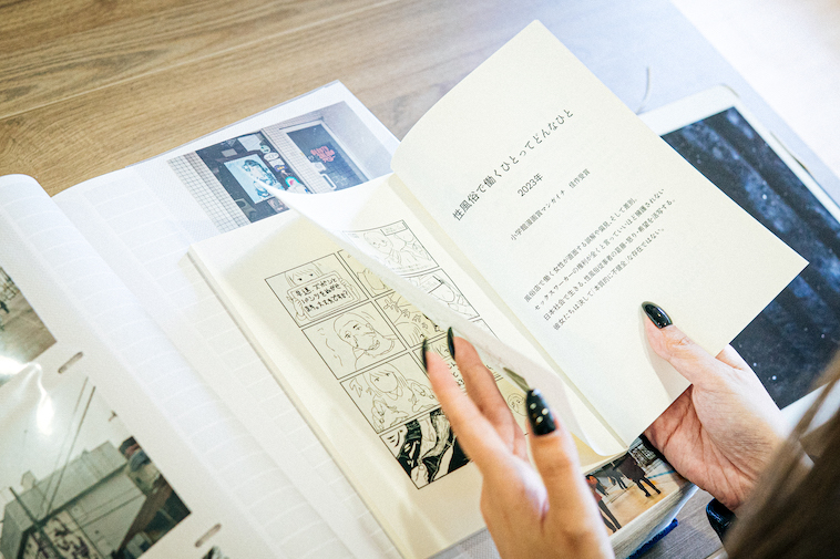 【写真】作品集のページをめくっている