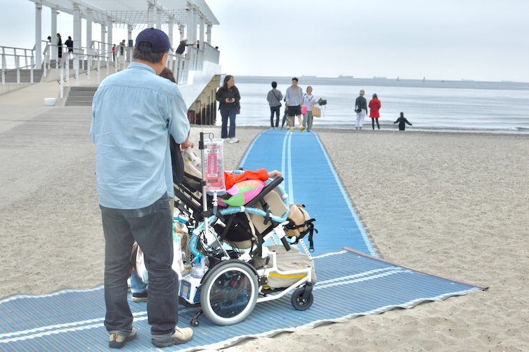 【写真】車椅子を押しながらモビマットの上を通る人