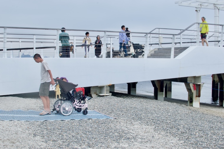 【写真】モビマットの上で車椅子に背を向けて引っ張っている家族
