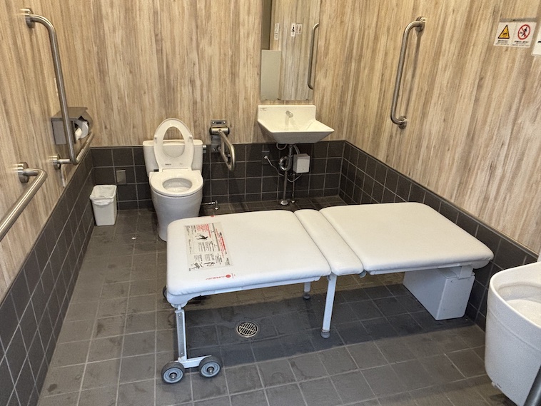 【写真】だれでもトイレの写真。便器や手すり、オストメイト対応設備、ユニバーサルシートが備わっている