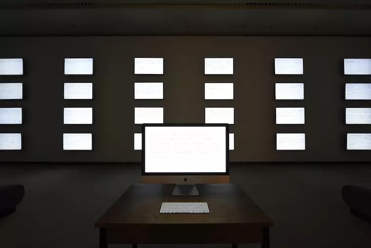 【写真】暗闇で光るいくつもの画面。手前にある1台のパソコンにはキーボードも置いてある。